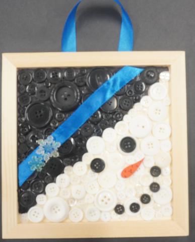 Snowman made from black and white buttons in a frame  