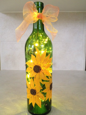 Paint with Paula green wine bottle with lights inside and sunflowers painted on outside